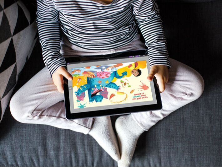 Picture of a child holding a tablet that displays an ebook