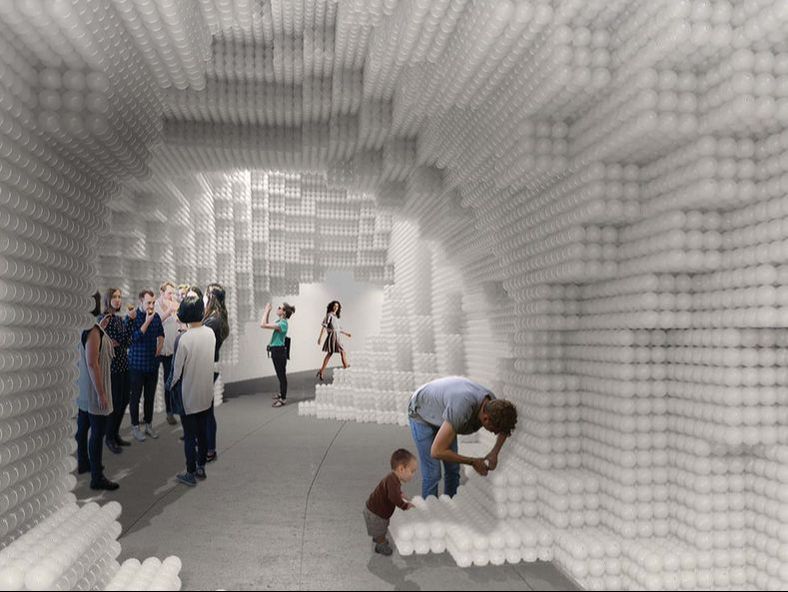 Picture of people inside a cave constructed out of white play balls